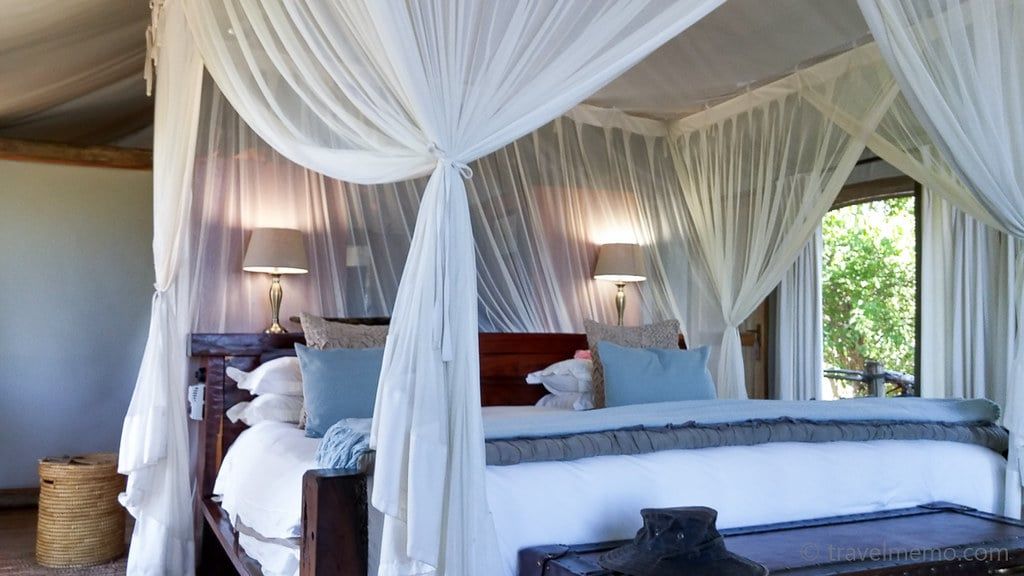 A canopy bed draped with mosquito netting inside a luxury tented safari suite at Tubu Tree Camp in the Okavango Delta, Botswana.